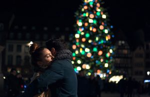 couple hugging by lit christmas tree