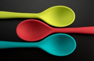 green, red and teal spoon on black background