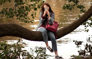 woman on phone sitting on tree branch