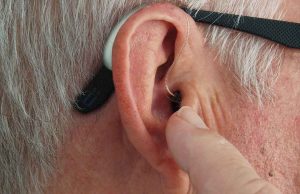 ear with hearing device and black glasses with grey hair