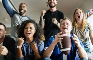 group of men and woman cheering holding a football