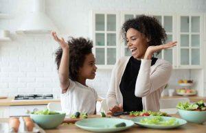 mom and daughter in black and white shirts high fiving at table of food